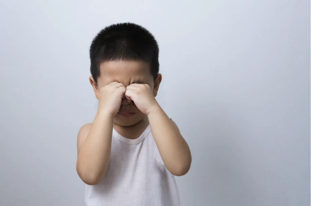 Asian child rubbing his eyes, a habit often from a common eyelid condition called epiblepharon