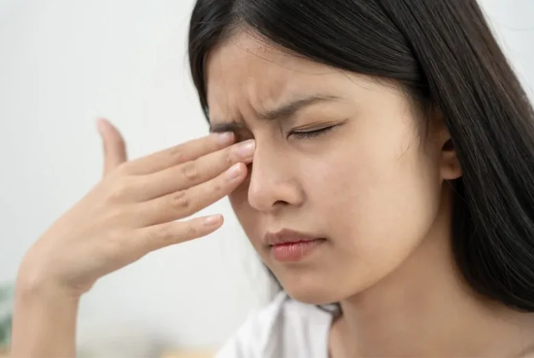 Asian woman rubbing her irritated right eye