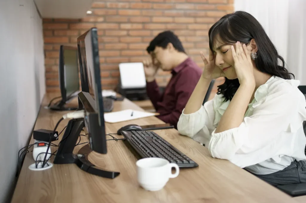 Office worker rubbing her temples from computer screen strain, demonstrating how eye strain relates to whether can dizziness be a sign of eye problems.